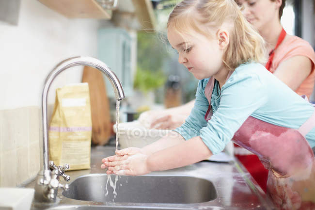 Девушка моет руки на кухне — стоковое фото