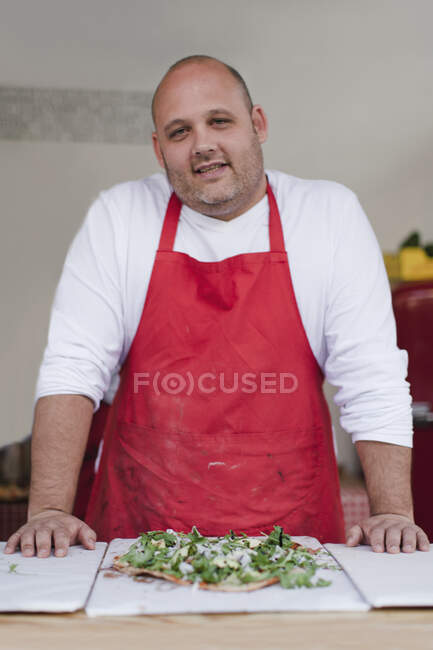 Chef with pizza in kitchen — Stock Photo