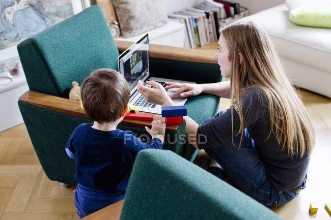 Mitte erwachsene Frau und kleiner Sohn schauen auf Laptop im Wohnzimmer — Stockfoto