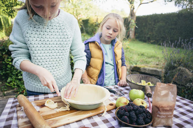 Two girls making a pie in countryside garden — Stock Photo