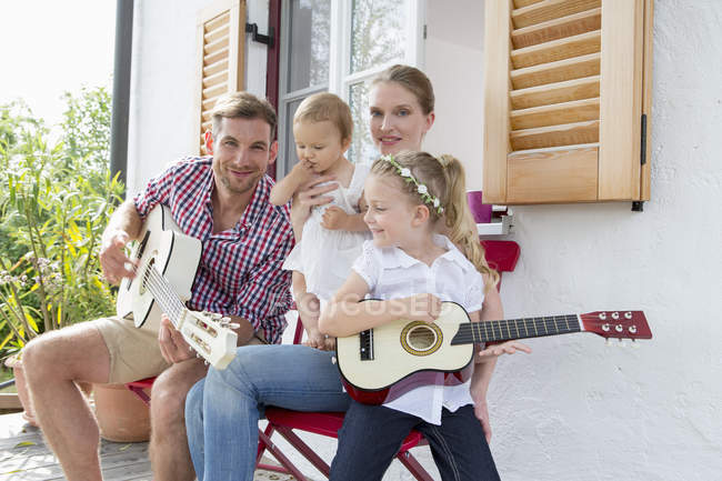 Отец играет на гитаре с семьей — стоковое фото