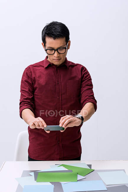 Jovem designer masculino fotografando amostras de cores com smartphone — Fotografia de Stock