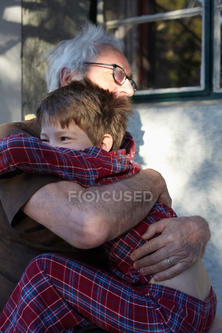 Старший мужчина обнимает внука на улице — стоковое фото