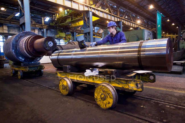 Worker cleaning metal in steel forge — Stock Photo