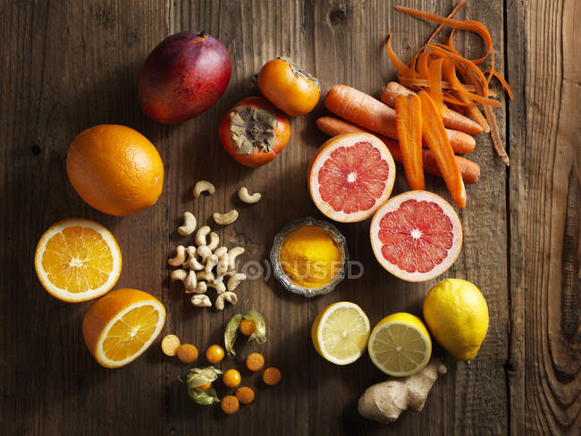 Vista superior de frutas y verduras de color naranja sobre fondo de grano de madera - foto de stock