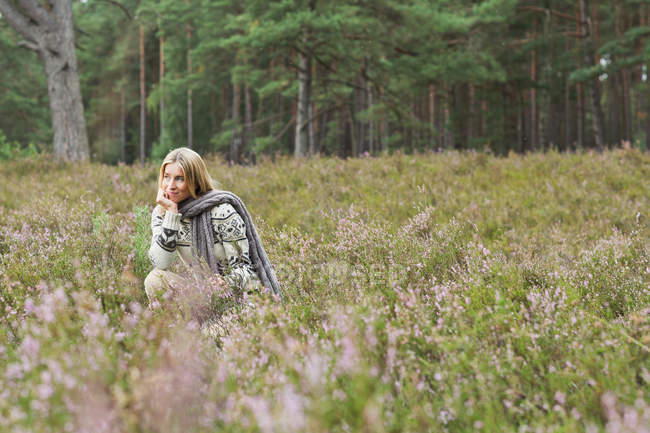 Femme adulte moyenne dans la prairie avec la main sur le menton — Photo de stock