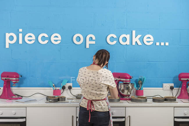 Вид сзади на молодую женщину, использующую блендер в пекарне — стоковое фото