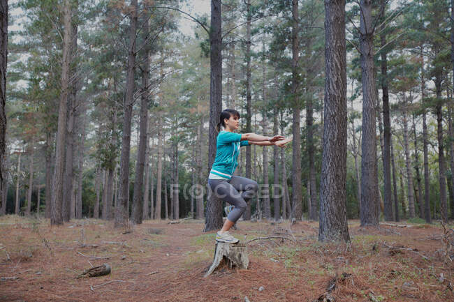 Woman balancing on stump in forest — Stock Photo