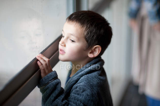 Giovane ragazzo guardando attraverso finestra portico — Foto stock