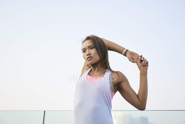 Young woman warming up and stretching arms in city — Stock Photo