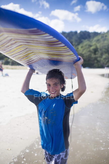 Niño surfista llevando tabla de surf - foto de stock