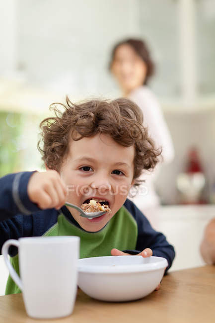 Boy eating breakfast in kitchen, focus on foreground — Stock Photo