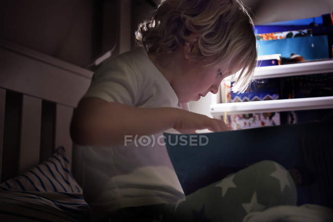 Junge liest auf Bett — Stockfoto