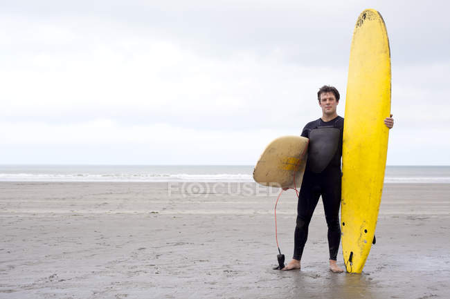 Porträt eines Mannes mit Surfbrettern am Strand — Stockfoto