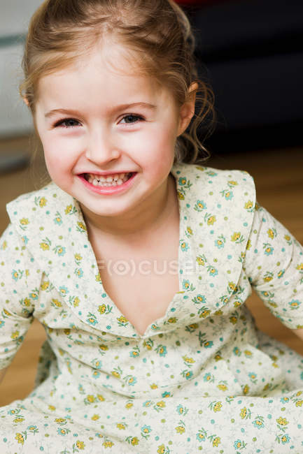 Портрет улыбающейся девушки, сидящей в помещении — стоковое фото
