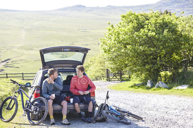 Cyclists sitting on car boot taking a break — Stock Photo