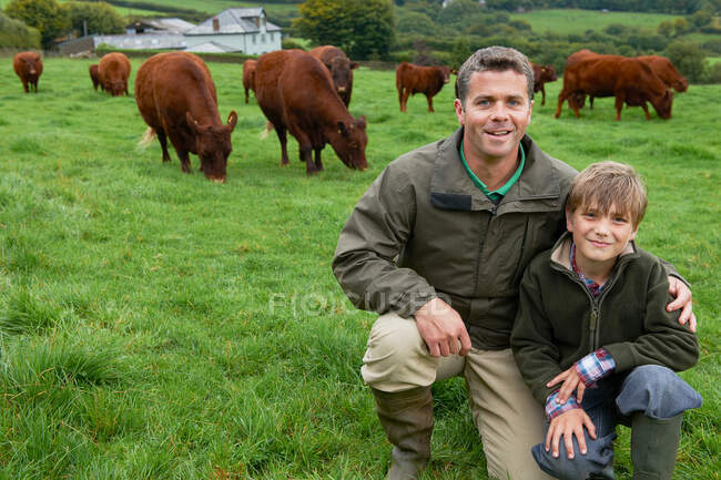 Padre e hijo en granja con vacas - foto de stock
