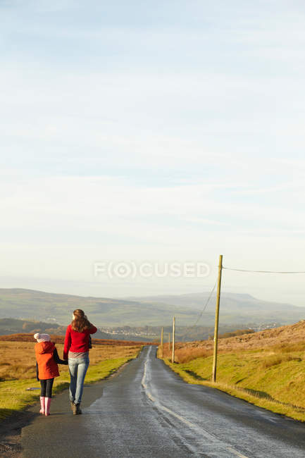 Мать и дочь на сельской дороге, вид сзади — стоковое фото