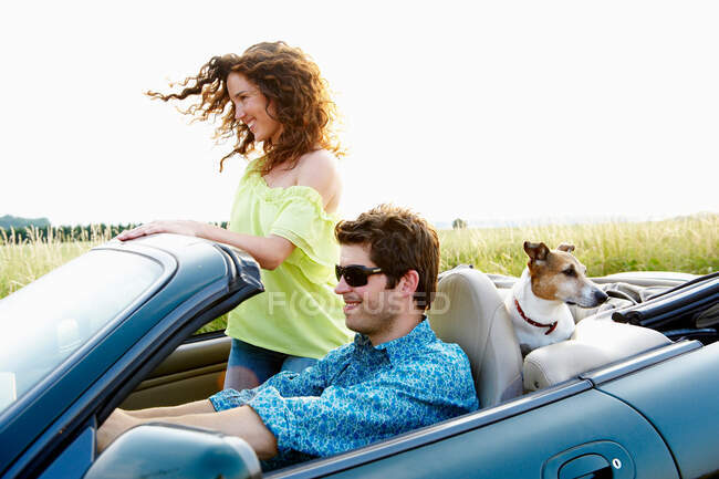 Пара в кабриолете, с собакой — стоковое фото