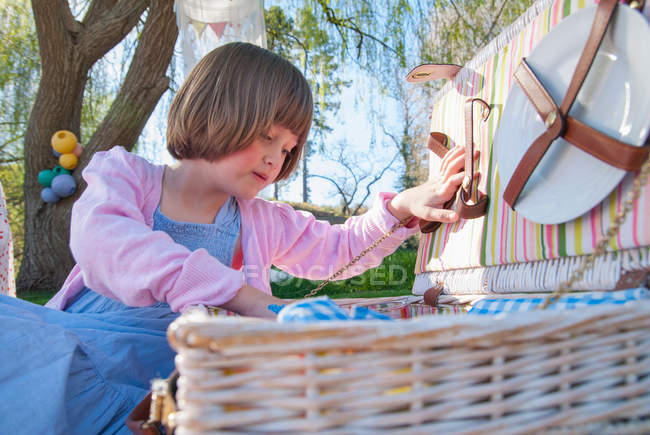 Menina desembalar cesta de piquenique ao ar livre — Fotografia de Stock