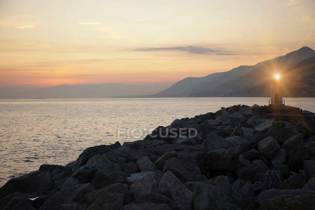 Farol brilhando sobre praia rochosa — Fotografia de Stock