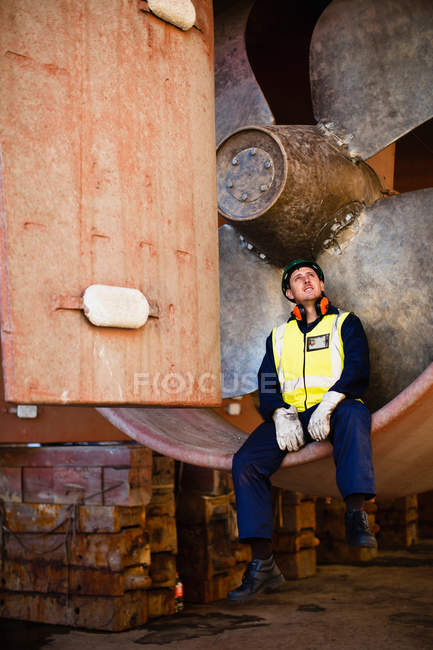 Worker sitting in propeller on dry dock — Stock Photo