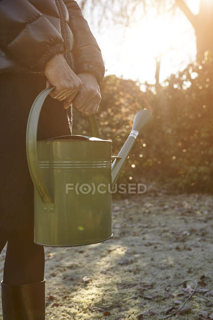 Seniorin steht im Garten, hält Gießkanne in der Hand, Mittelteil — Stockfoto