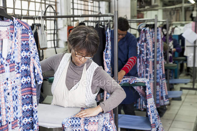 Arbeiter bügelt Kleid in Bekleidungsfabrik — Stockfoto