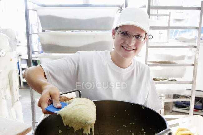 Baker scooping bread dough — Stock Photo