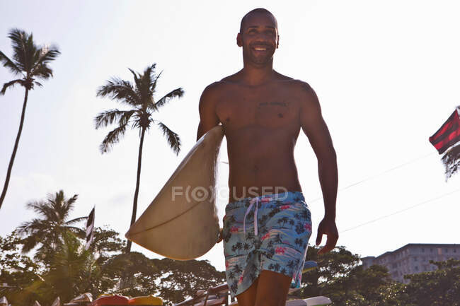 Hombre adulto medio llevando tabla de surf - foto de stock