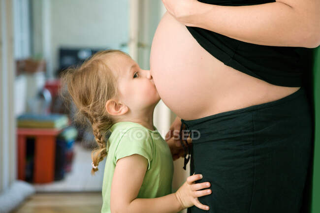 Chica besando embarazada madre? s vientre - foto de stock