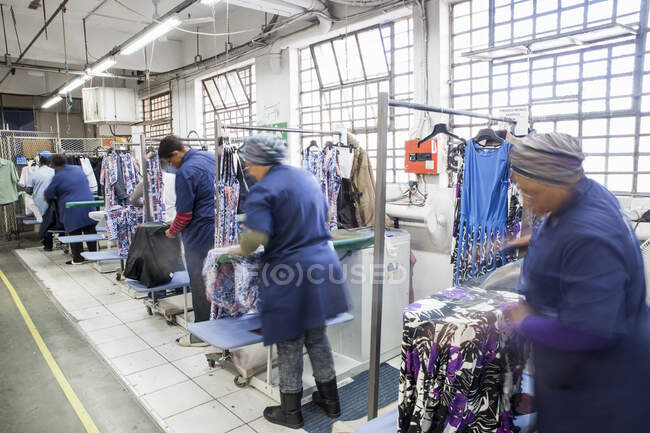 Trabajadores planchar vestido en fábrica de prendas de vestir - foto de stock