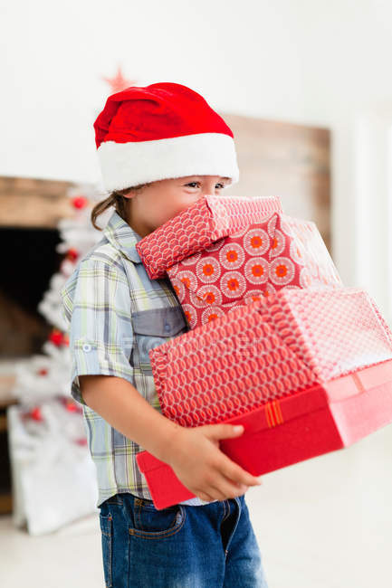 Boy in Santa hat with Christmas gifts — Stock Photo