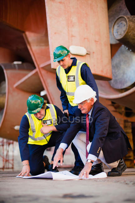 Workers reading blueprints on dry dock — Stock Photo