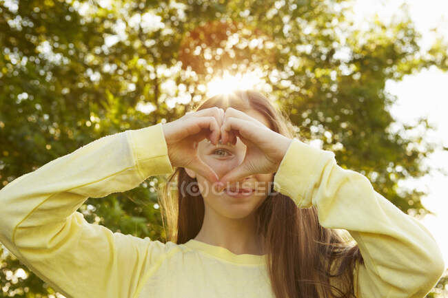 Portrait de fille faisant forme de coeur avec les mains dans le parc — Photo de stock