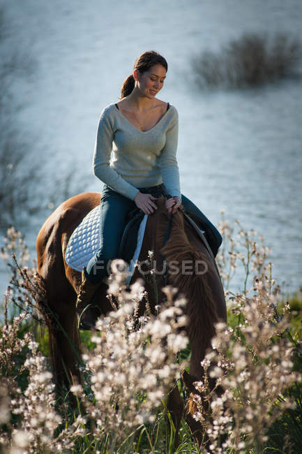 Mujer montando a caballo en campo rural - foto de stock