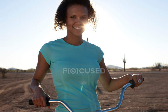Женщина с велосипедом в пустыне пейзаж — стоковое фото