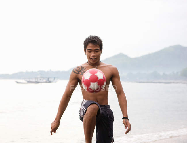 Chico jugando fútbol en la playa - foto de stock