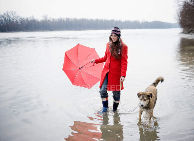Jeune femme tenant parapluie avec chien — Photo de stock