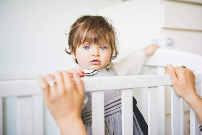 Portrait of female toddler staring from crib — Stock Photo