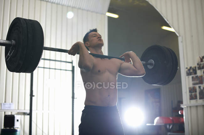 Moyen homme adulte levant haltère dans la salle de gym — Photo de stock