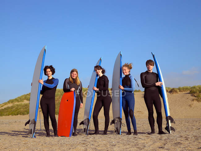 Cinco surfistas adolescentes en una playa - foto de stock