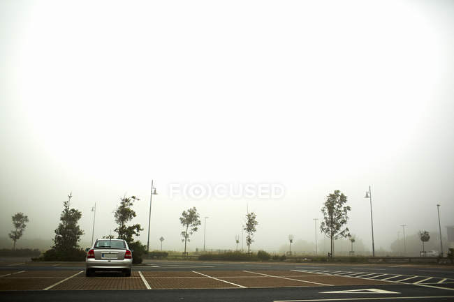 Carro estacionado no parque de estacionamento nebuloso — Fotografia de Stock