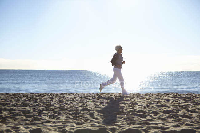 Mulher madura correndo na praia — Fotografia de Stock
