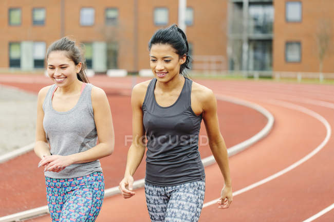 Due giovani donne che camminano lungo la pista da corsa — Foto stock