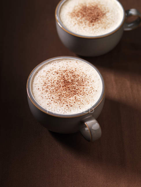 Duas xícaras de cappuccino com canela, vista superior — Fotografia de Stock