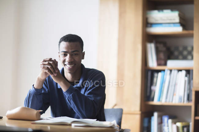 Portrait of happy young male high school student sitting at desk — Stock Photo