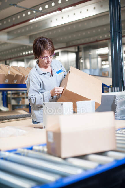 Female warehouse worker labeling box for conveyor belt — Stock Photo