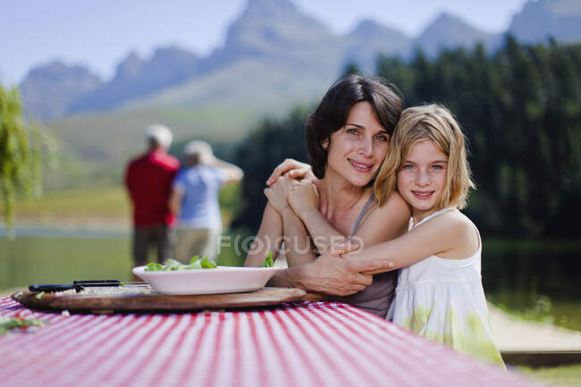 Mãe e filha abraçando no piquenique — Fotografia de Stock