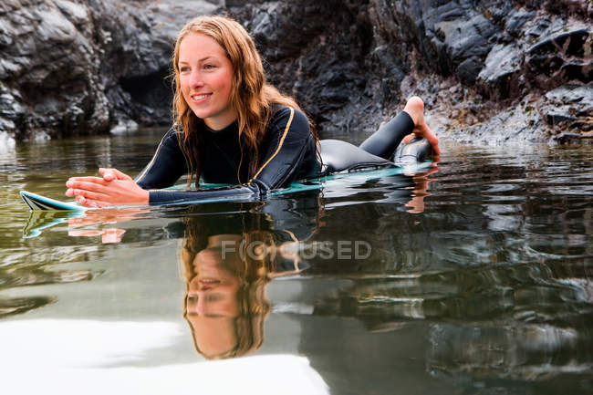 Женщина лежит на доске для серфинга в воде — стоковое фото